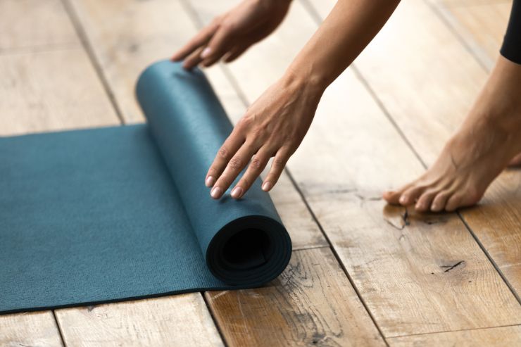 mani di donna che srotolano un tappetino da yoga